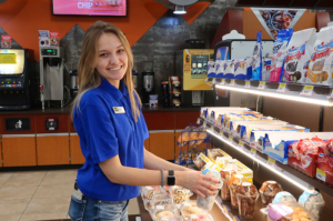 A happy blonde woman smiles as she stocks a large display of Hostess snack cakes.